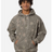 A man wearing a gray camouflage hoodie with a tree branch print, standing against a light gray background.