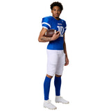 Athlete in a blue Champro Game Day jersey holding a football, wearing white padded football pants and blue socks.