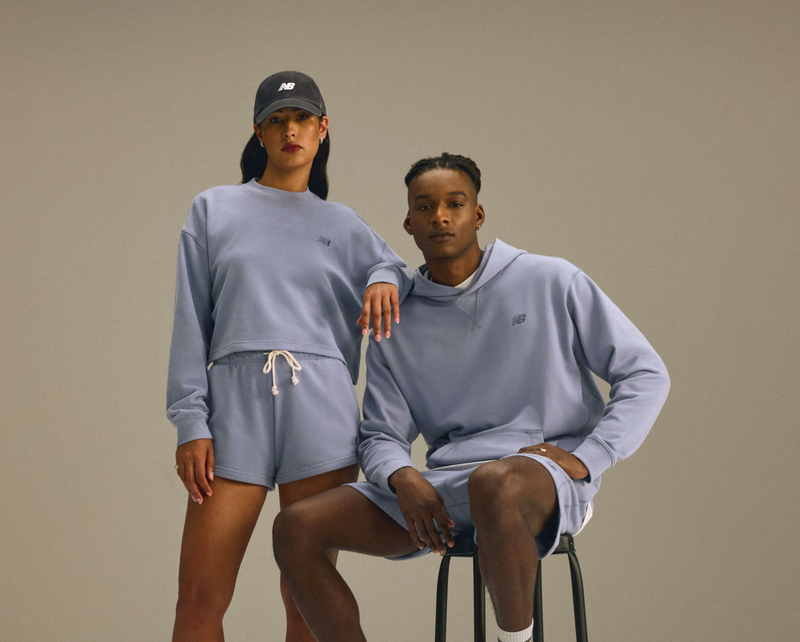 Two people wearing matching light blue outfits against a beige background