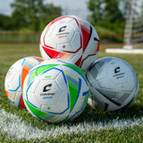 Champro Orix soccer balls stacked on a grassy field near a goal